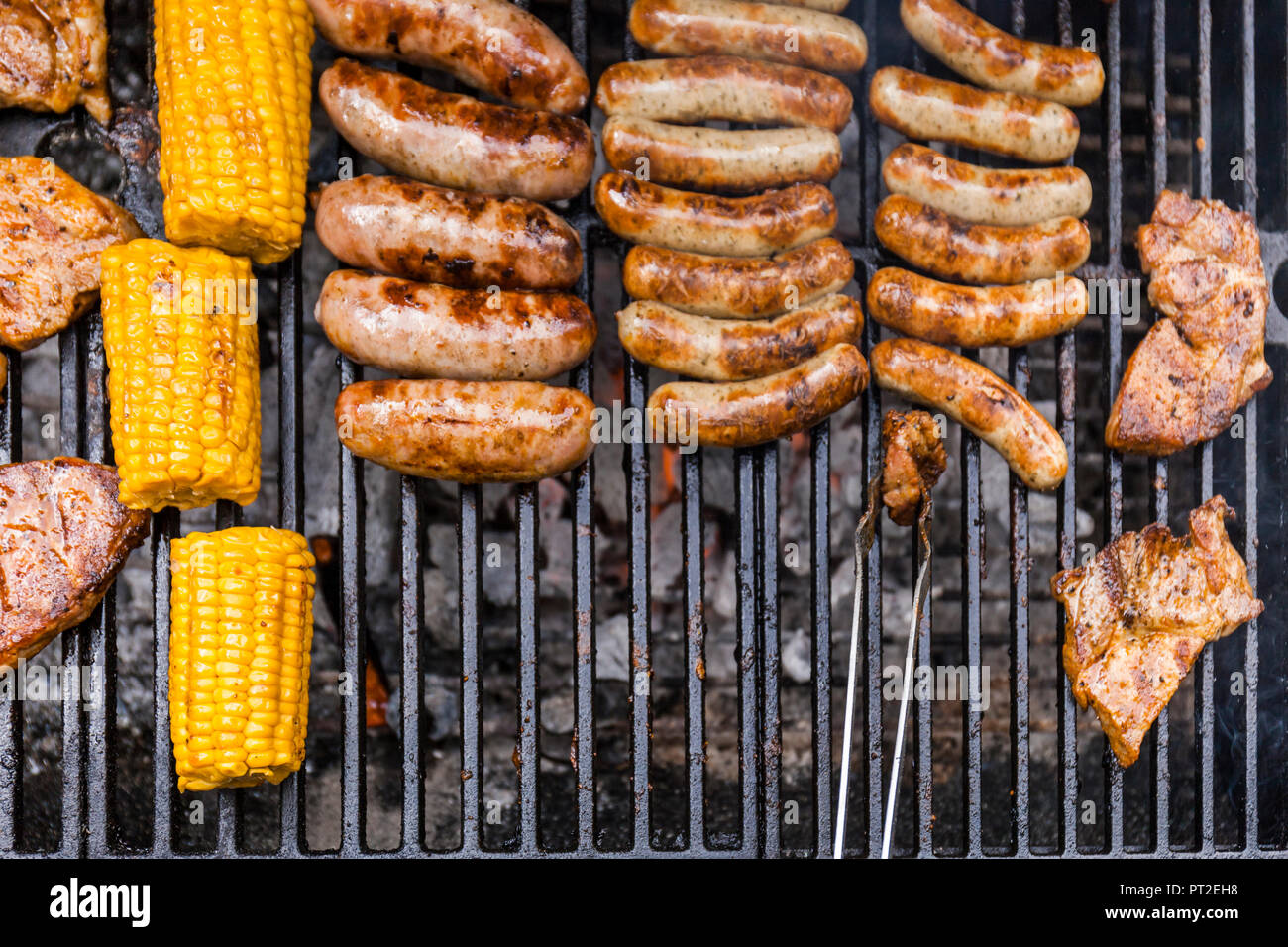 Different meat, maize and fried sausages on barbecue grill Stock Photo