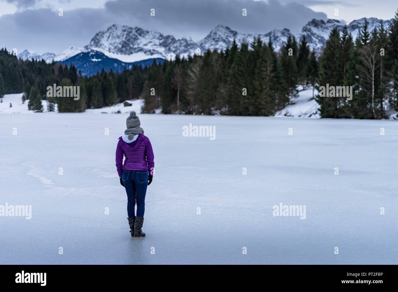Europe, Germany, Bavaria, woman standing on the frozen Geroldsee in Karwendel and marveling at the mountain panorama Stock Photo