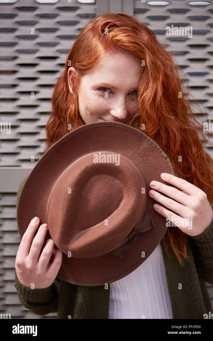 Portrait of smiling redheaded woman with brown hat Stock Photo