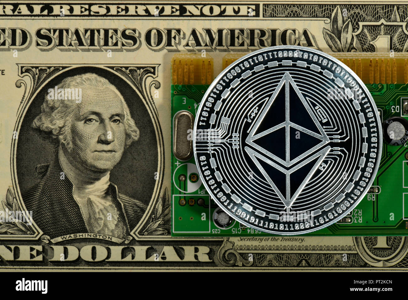 Symbolic image of digital currency, silver physical coin Ethereum on banknote 1 US dollar and printed circuit board Stock Photo