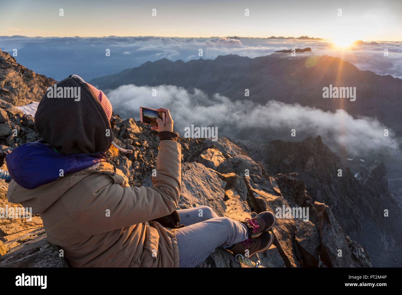Switzerland, canton Valais, district Entremont, Verbier, sunrise, 3329 m high Mont Fort, woman with smartphone photographing sunrise Stock Photo