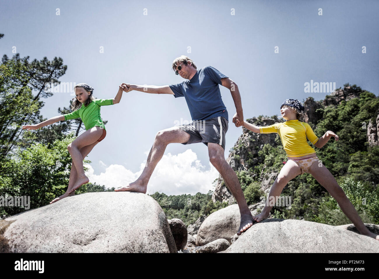 Father with 2 daughters barefoot in a river bed in Corsica Stock Photo