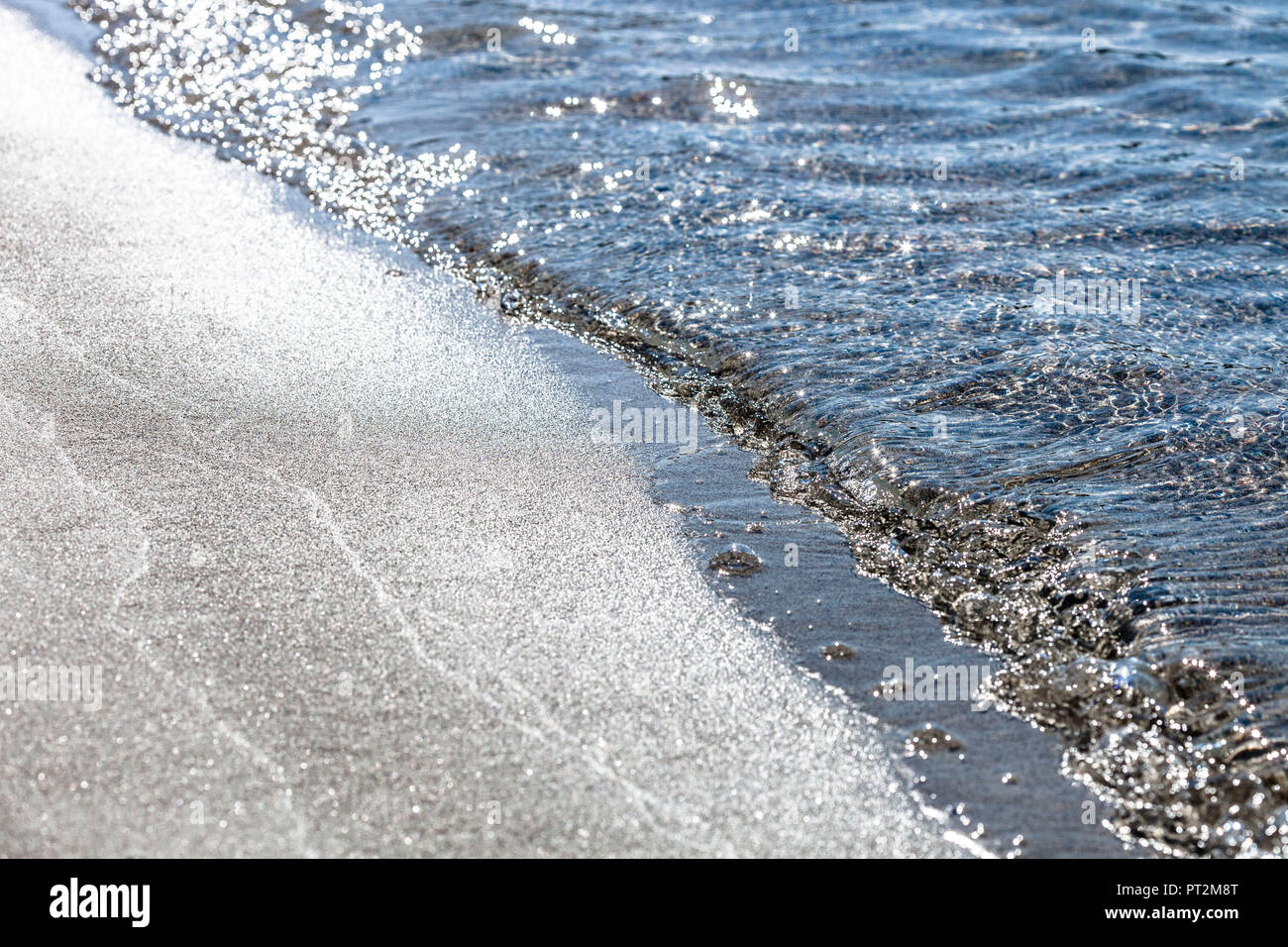 Small waves break in the backlight on the sandy beach of Palombaggia, Corsica Stock Photo