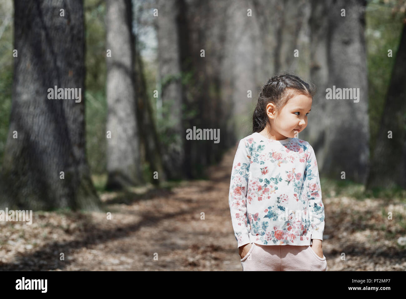 Littele girl standing in park, with hands in pockets Stock Photo
