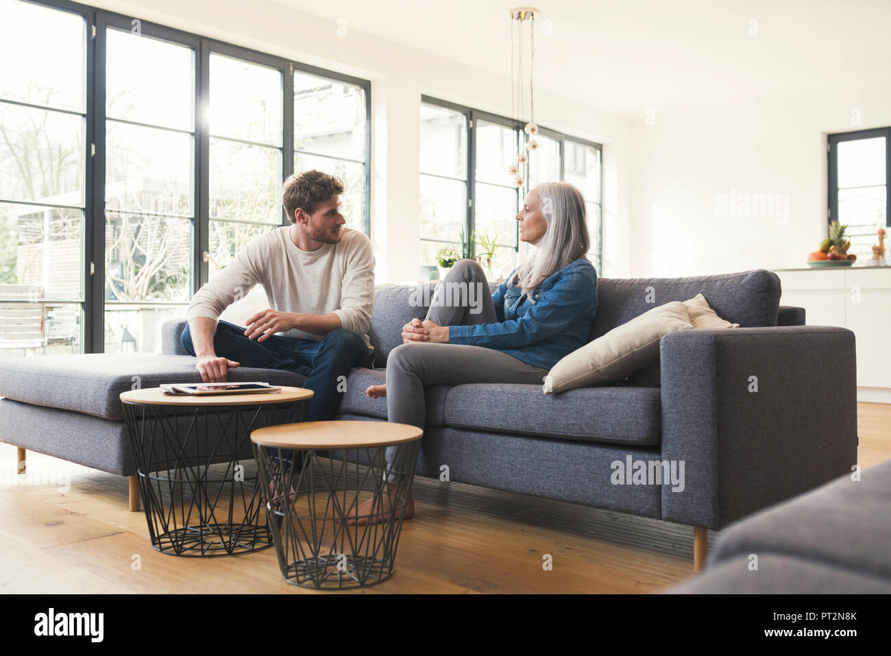 Son sitting on couch, talking to his mother Stock Photo