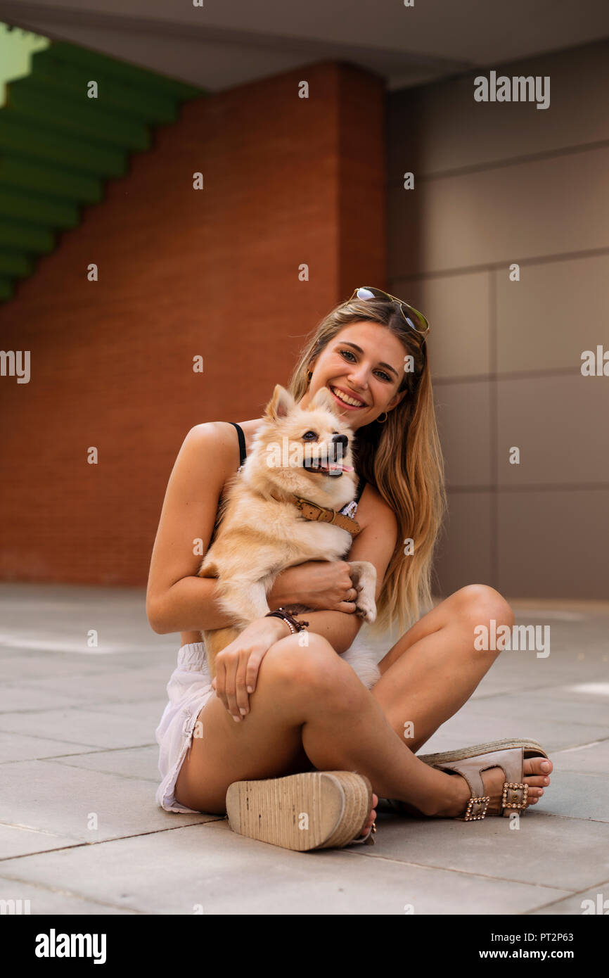 Smiling young woman sitting, holding her dog Stock Photo