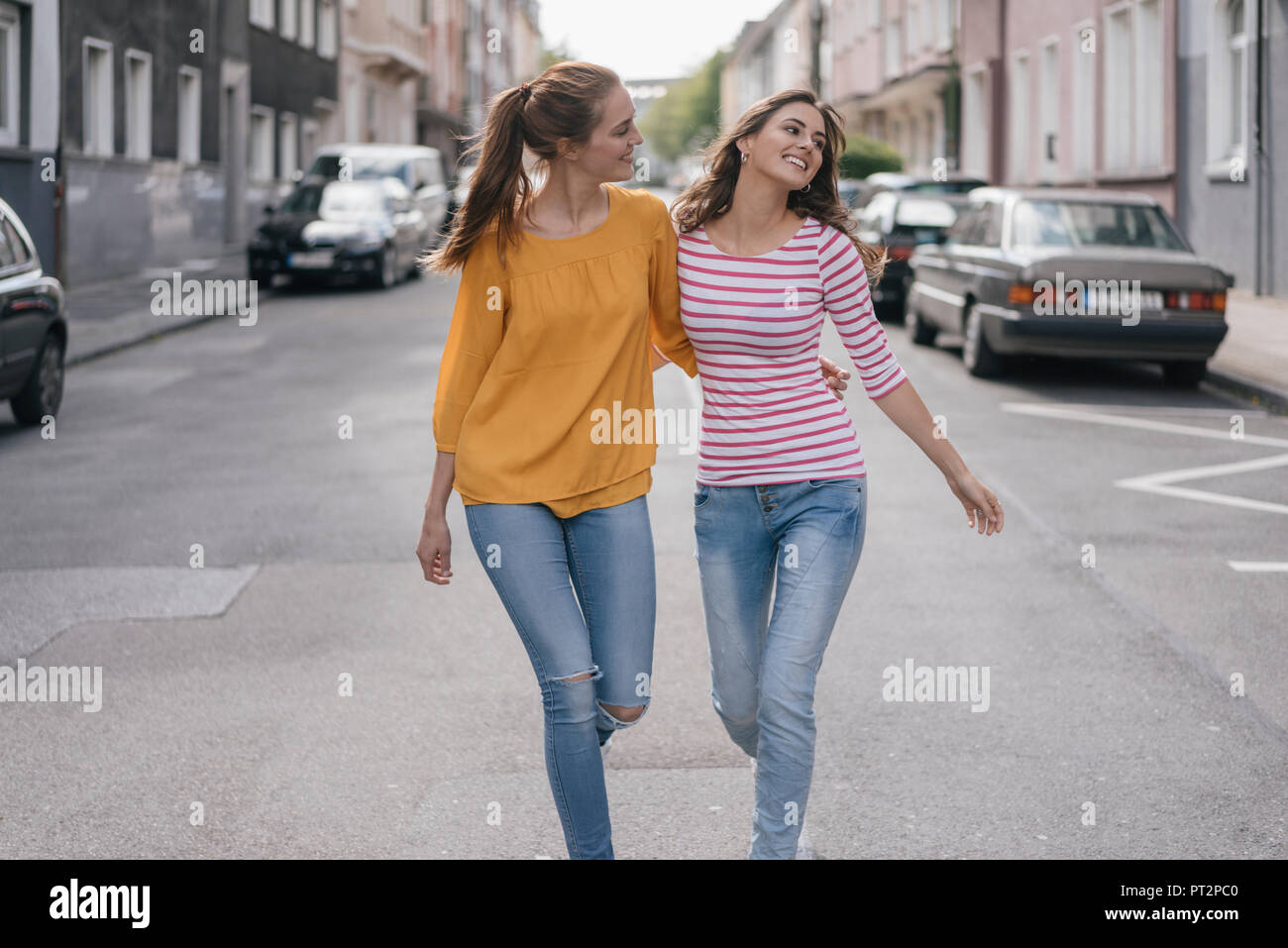 Two girlfriends having fun in the city, walking arm in arm Stock Photo