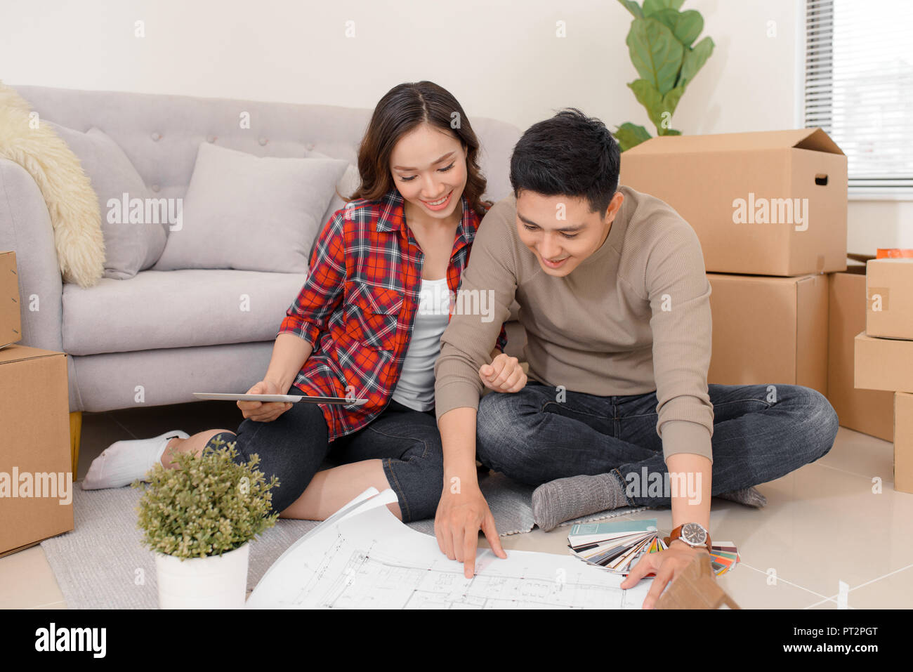 Happy young couple looking at blueprint planning new home interior design settling in, homeowners talking about remodeling ideas, discussing house arc Stock Photo