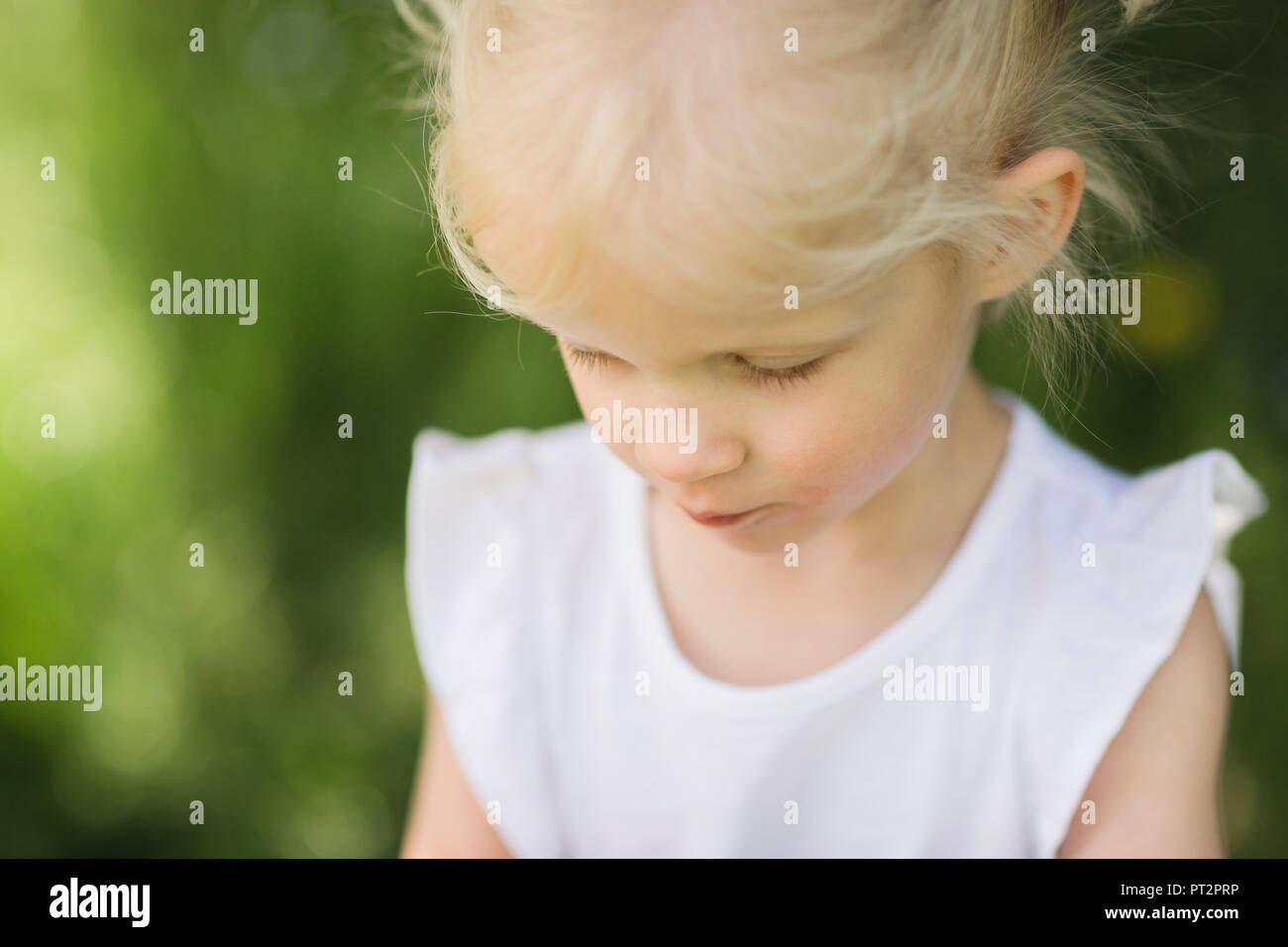 Blond little girl looking down Stock Photo