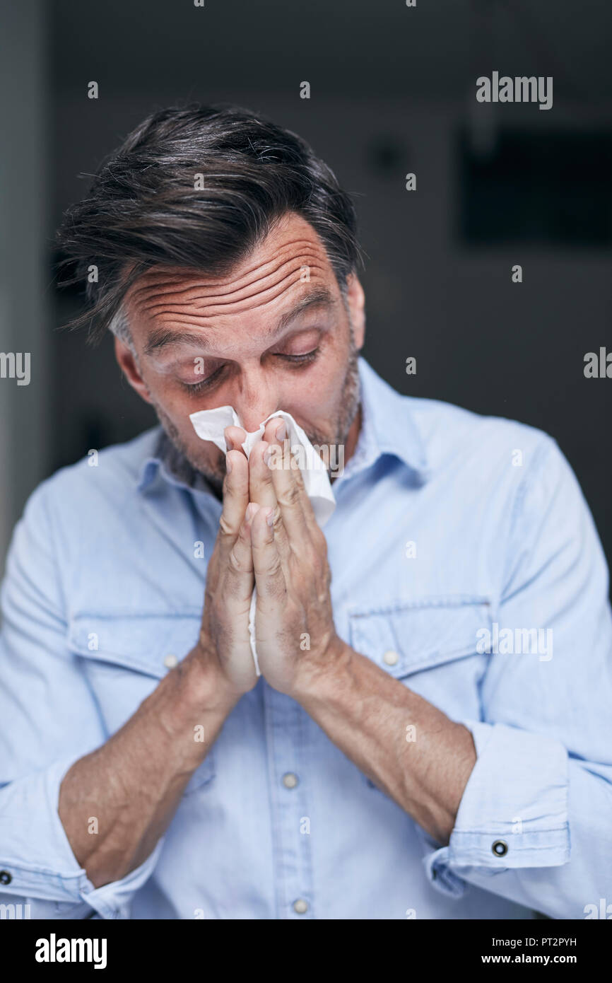 Portrait of man blowing nose Stock Photo