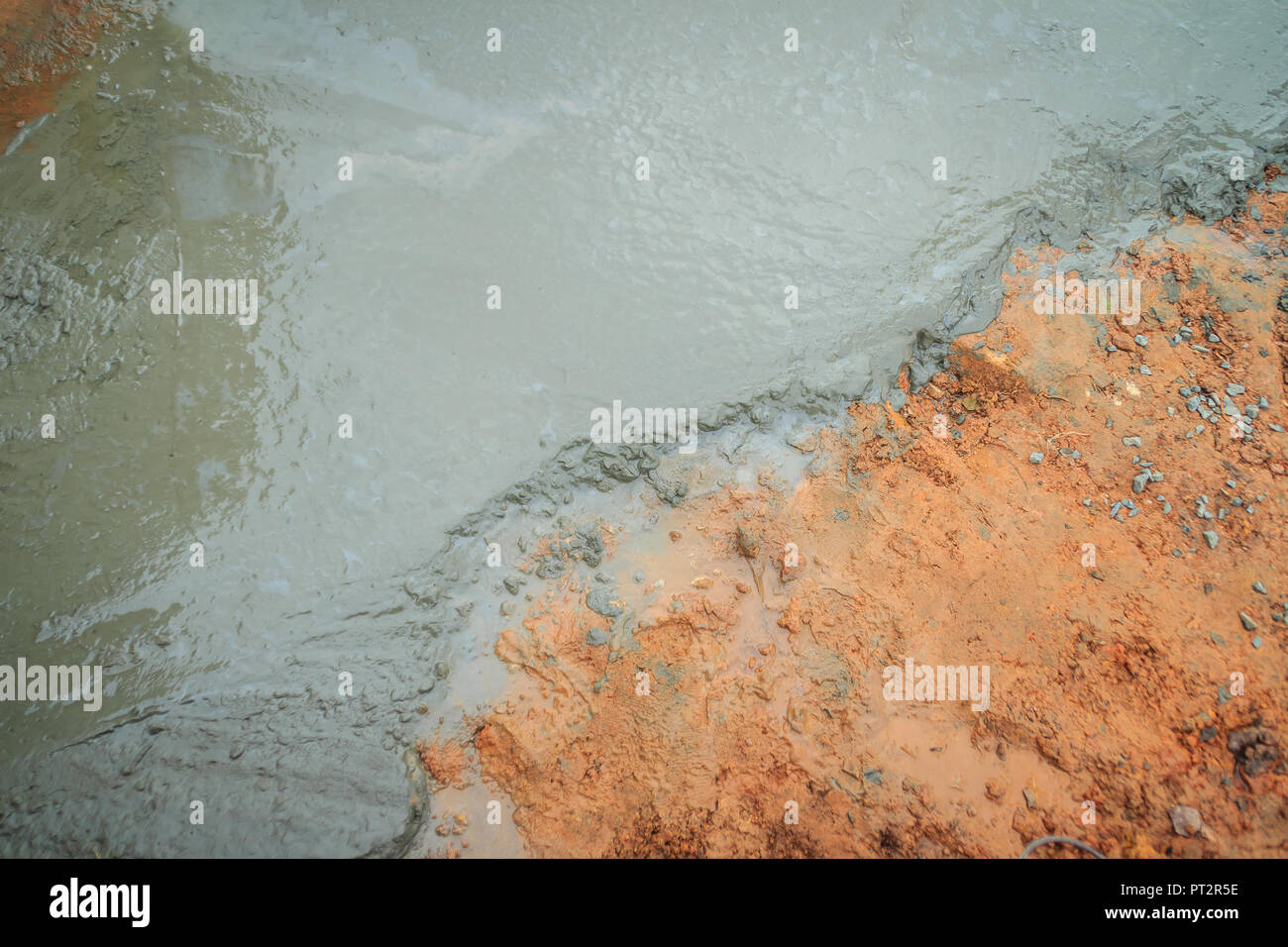 Liquid concrete poured and leveled on the ground. Wet concrete and red