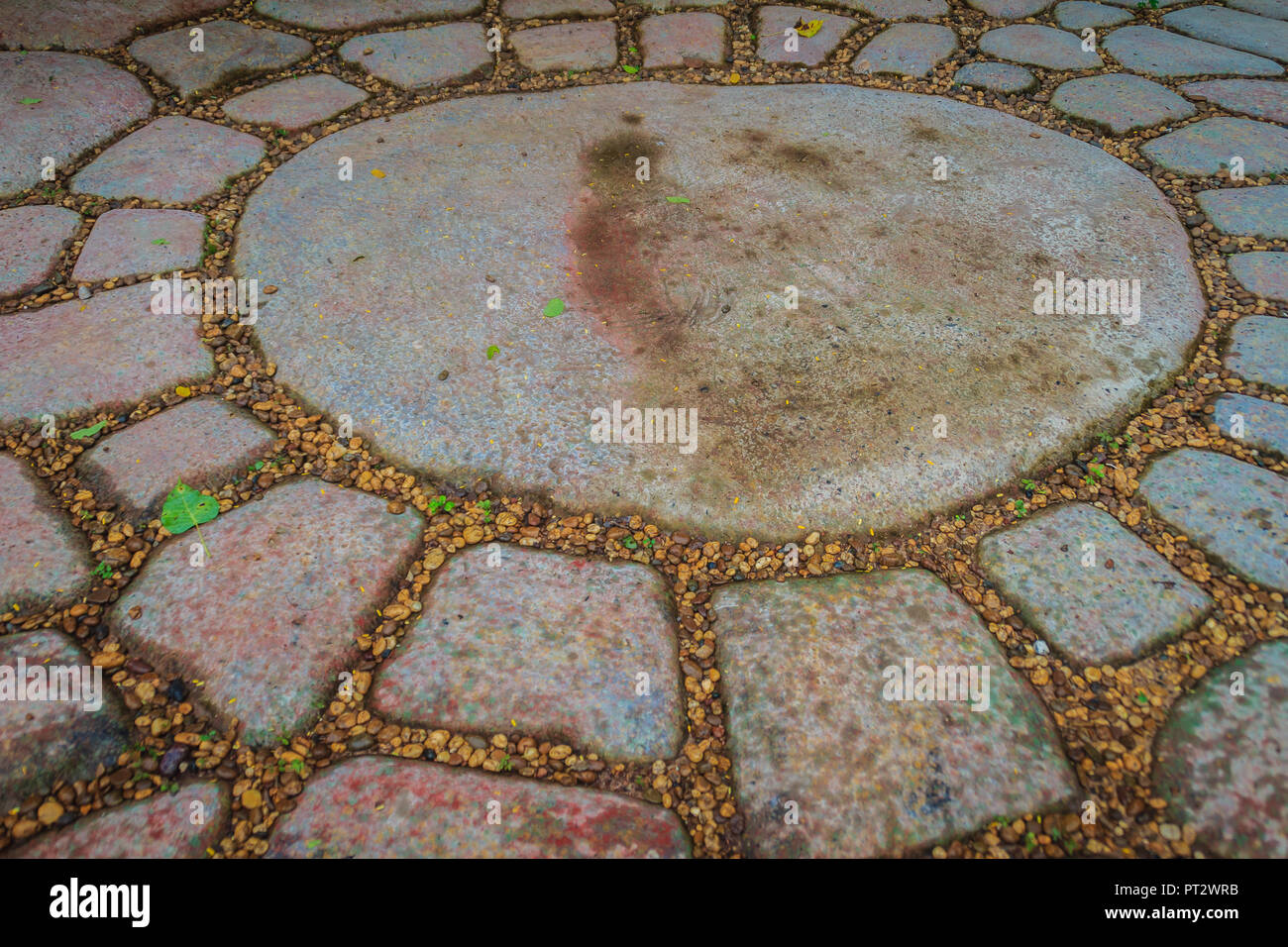 Vintage grungy gray pavement of cobblestones in a circle patterned background. Pavement of granite stone in organized arrangement background. Stock Photo