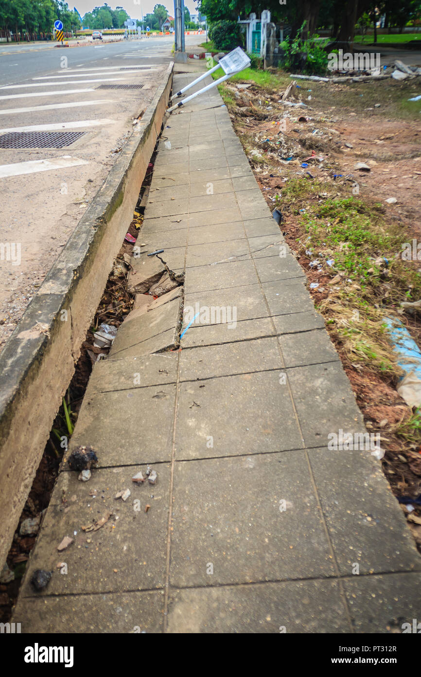 Concrete footpath is slipping after flood. Flood is causing erosion and landslide to the footpath in the city. Stock Photo