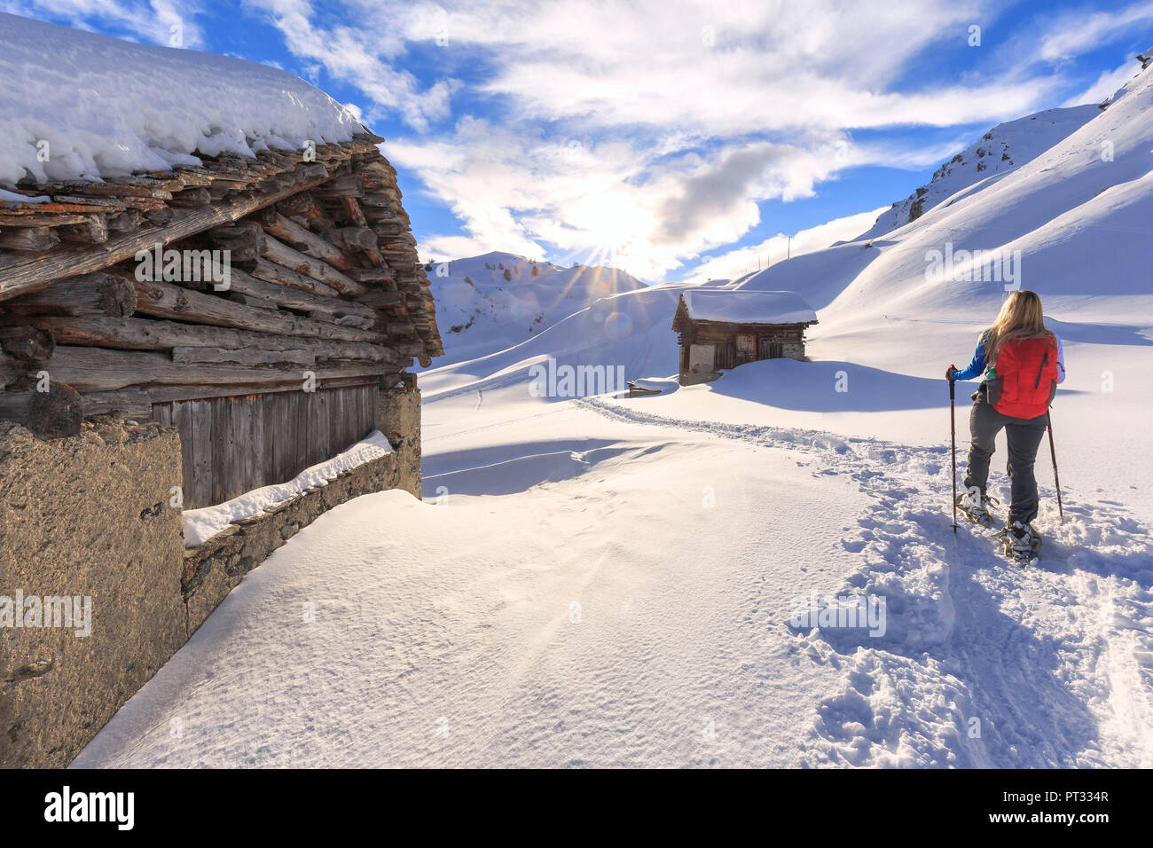 Young girl walks with snowshoes between traditional huts, Grevasalvas, Engadin Valley, Graubünden, Switzerland, Europe, Stock Photo
