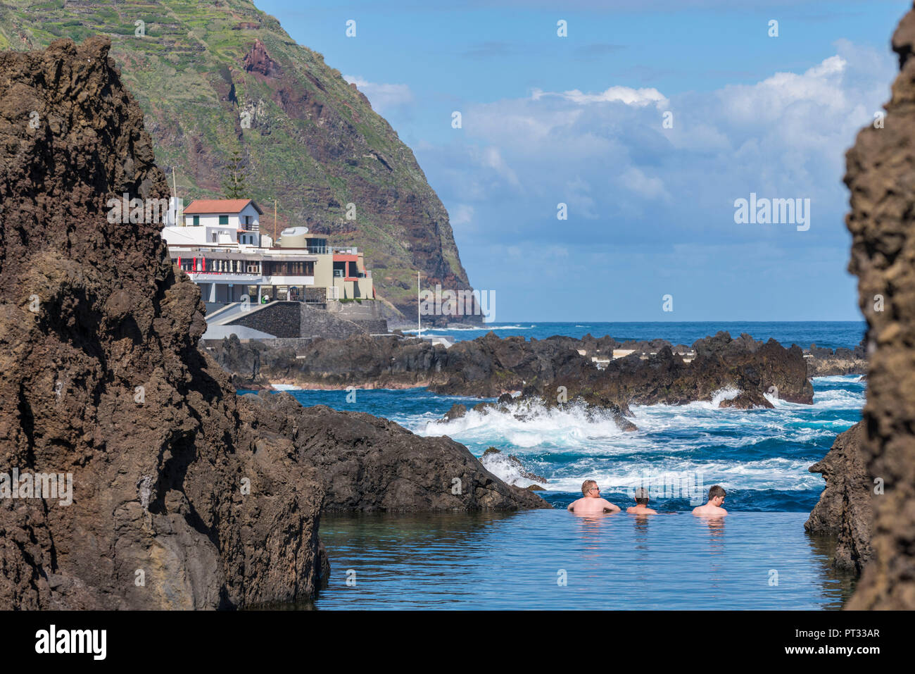 Three men bathing in the natural pools of Porto Moniz, Madeira region, Portugal, Stock Photo