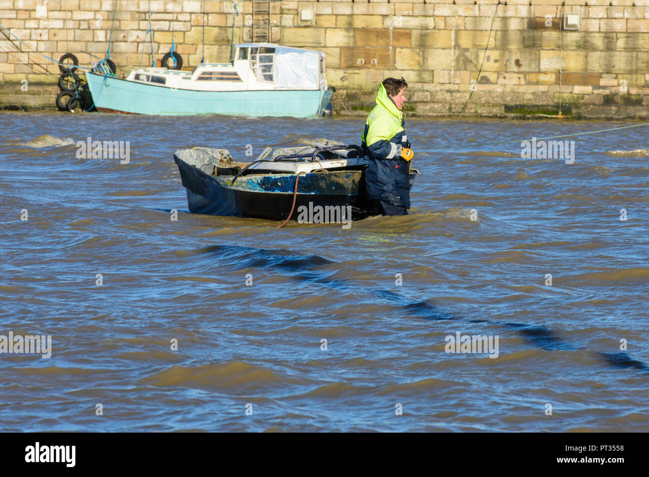 Workman in the water in Margate Harbour pulling a boat towards the