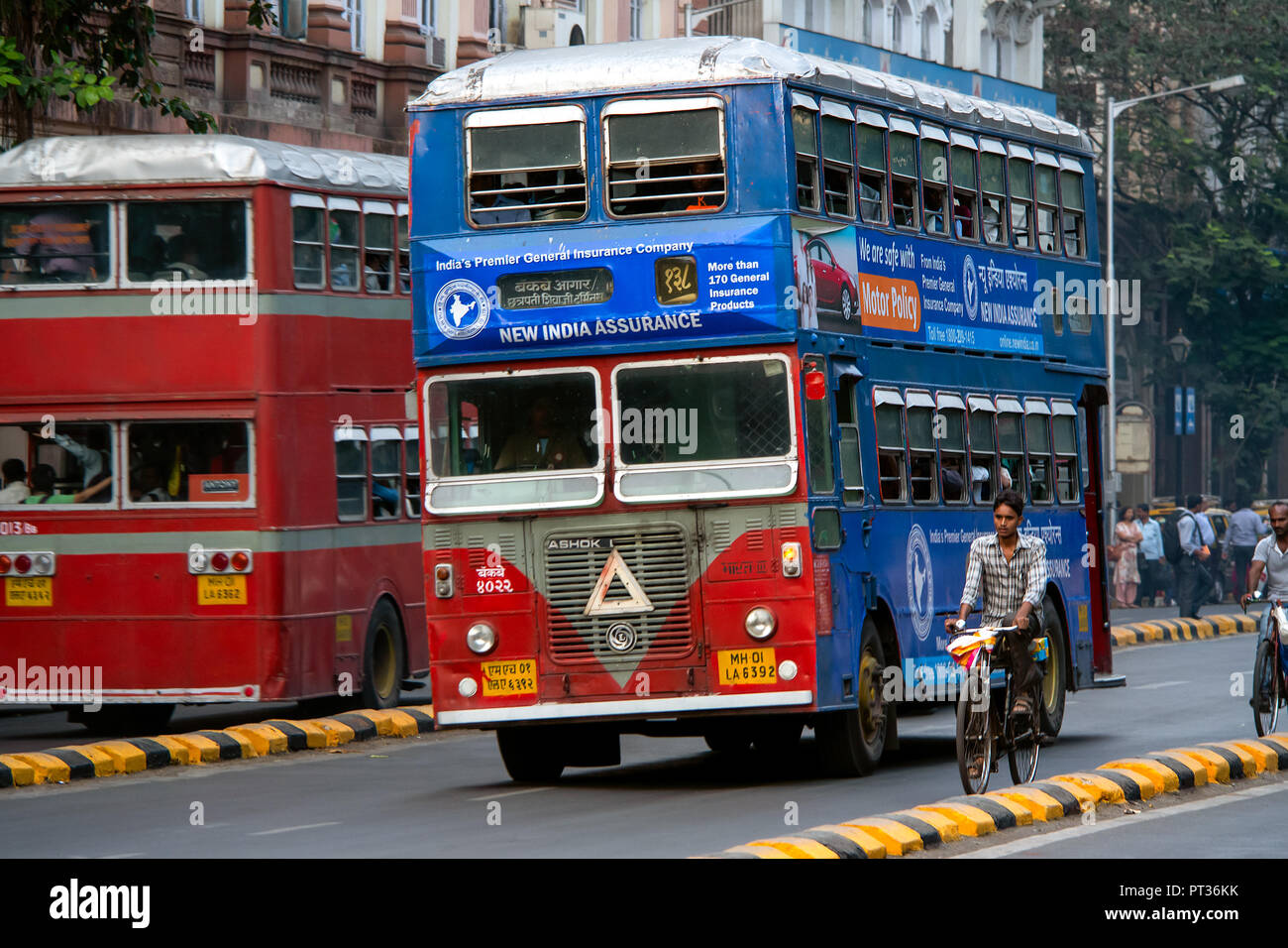 An old well used double decker 2 story Leyland bus passes some cyclists on the busy streets of Mumbai, India. Stock Photo