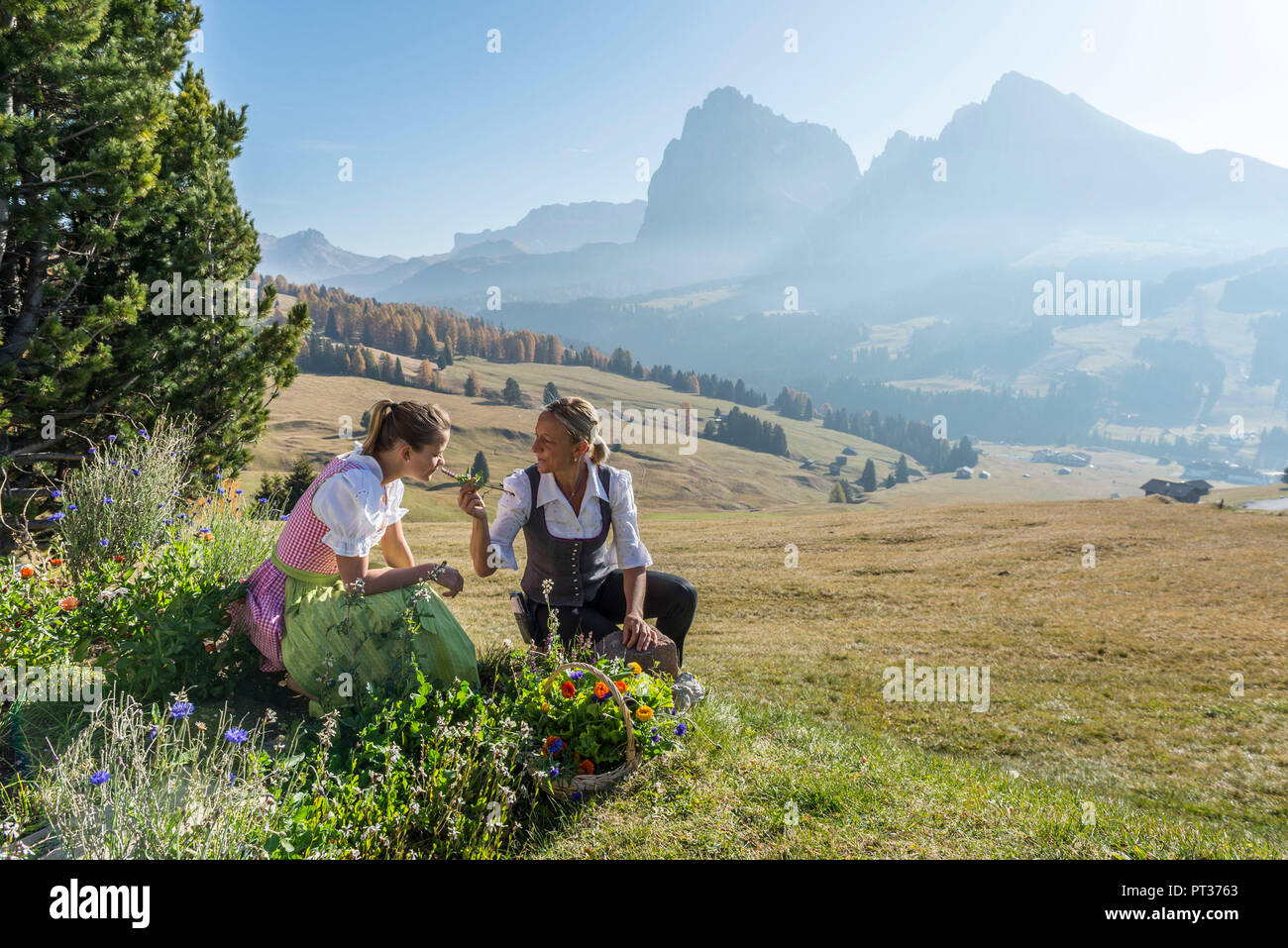 Helga and Maria Lageder with flower basket, Seiser Alm, near Castelrotto, Dolomites, South Tyrol, Italy Stock Photo