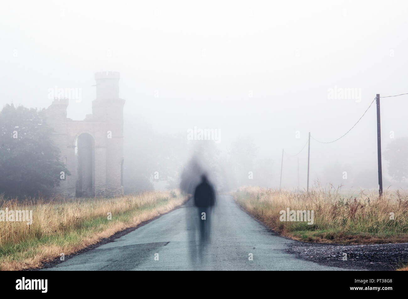 Blurred, ghostly figure walking down a foggy lane Stock Photo