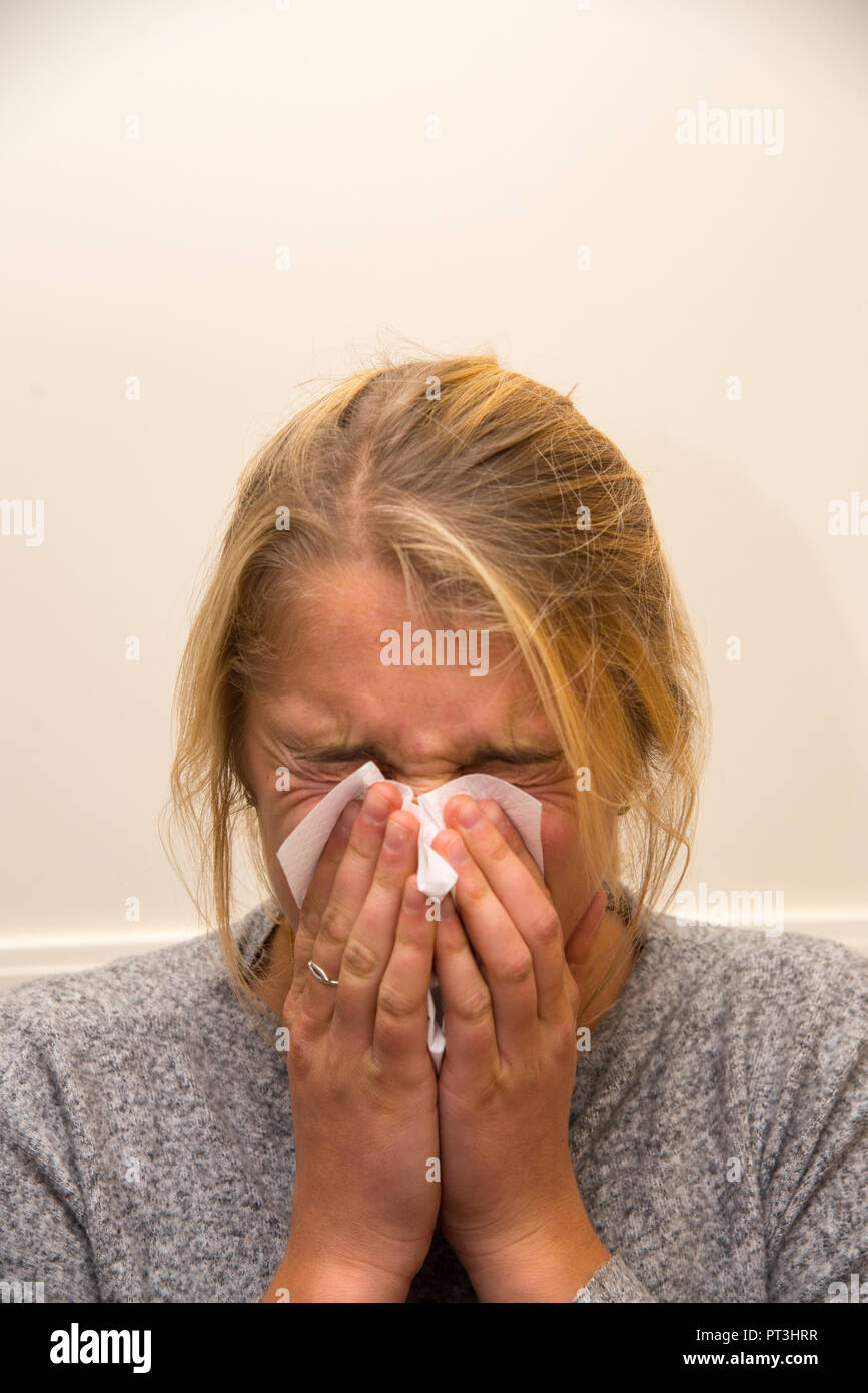 young woman sneezing her nose with a handkerchief Stock Photo