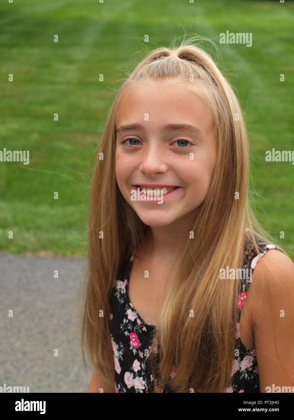 Cute smiling 10 year old girl with long hair and print dress. Stock Photo