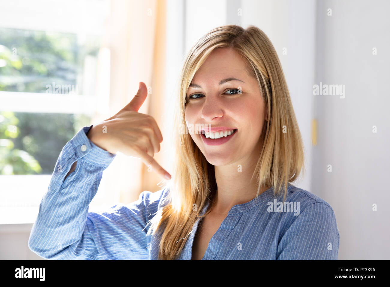 Portrait Of A Happy Young Businesswoman Making Call Me Gesture Stock Photo