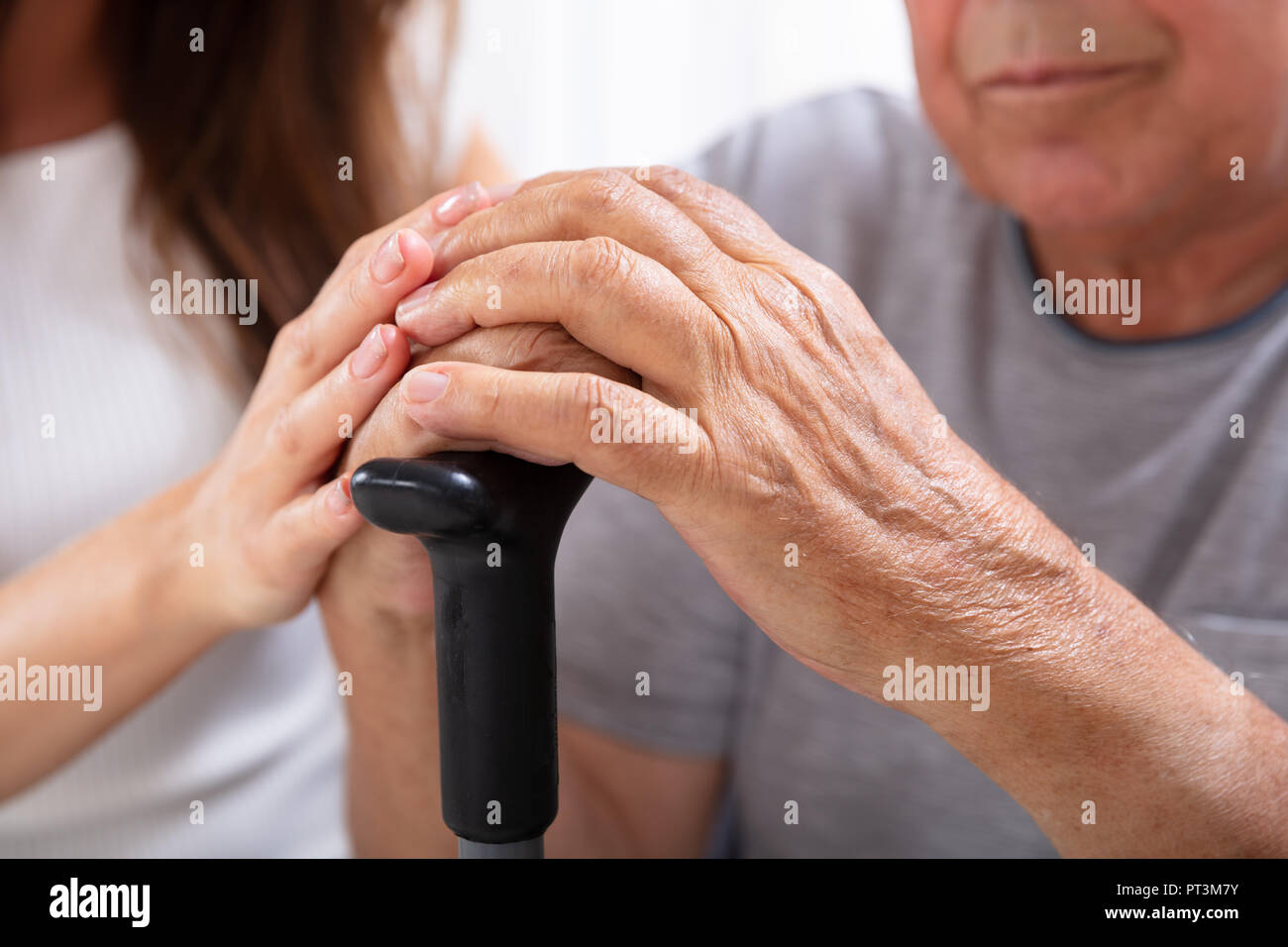 Close-up Of Senior Father And Daughter's Hand On Walking Stick Stock Photo