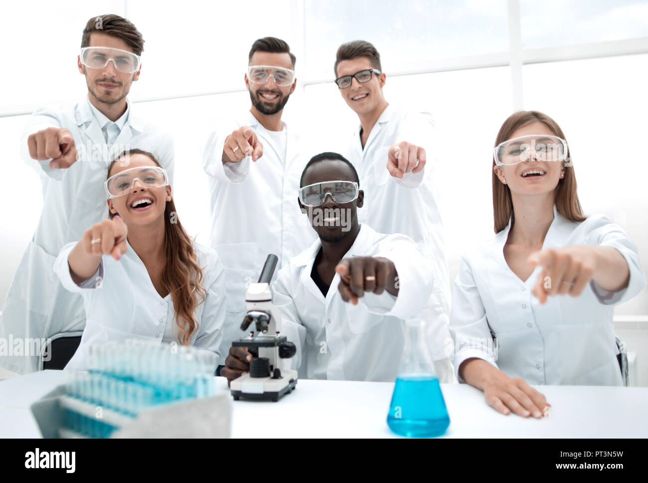 Group of scientists showing thumbs up sign and looking camera, researchers team presentation in