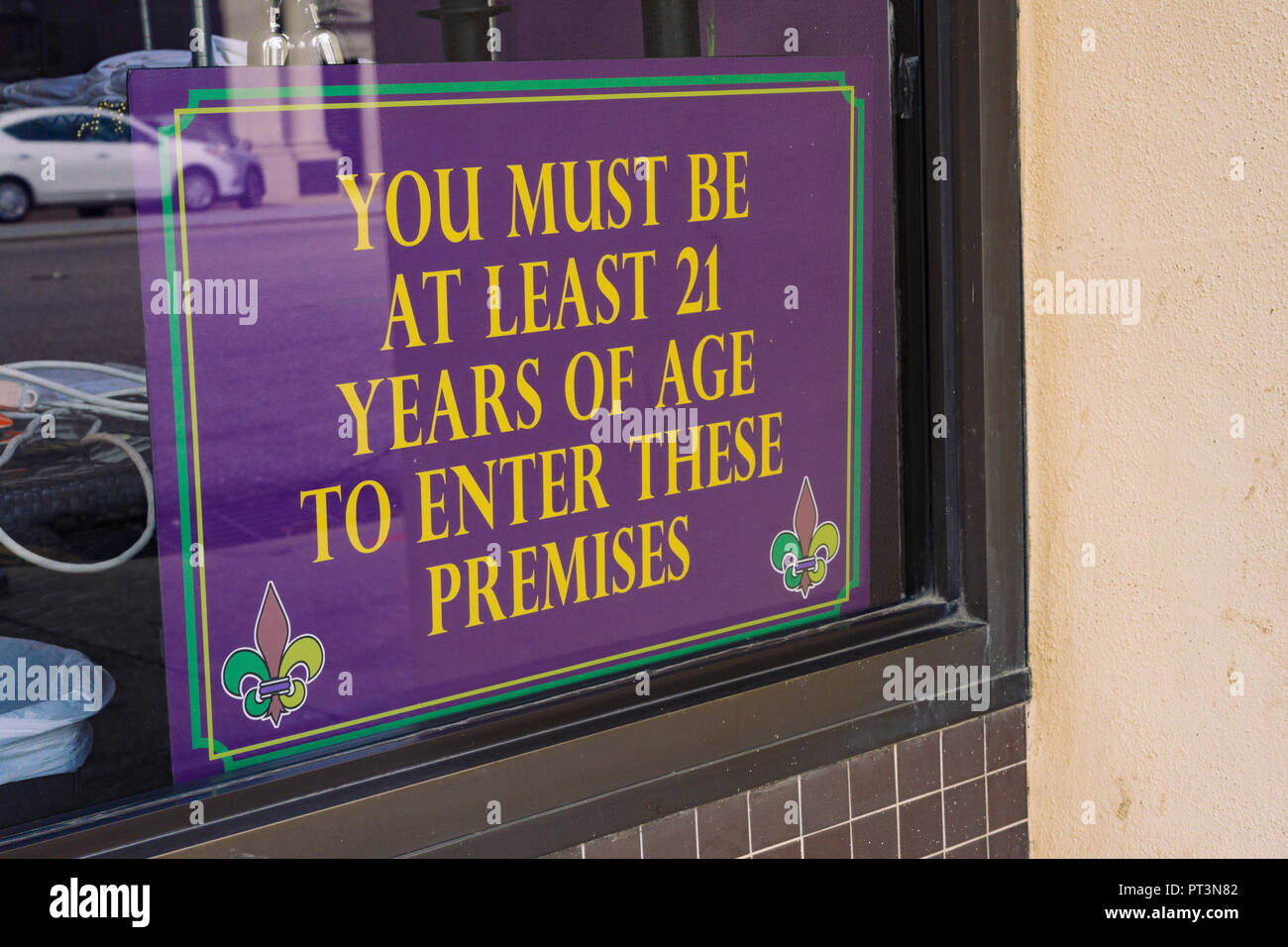 Minimum age restriction sign for drinking alcohol or alcoholic beverages in the window of a bar or tavern in downtown Montgomery Alabama, USA. Stock Photo