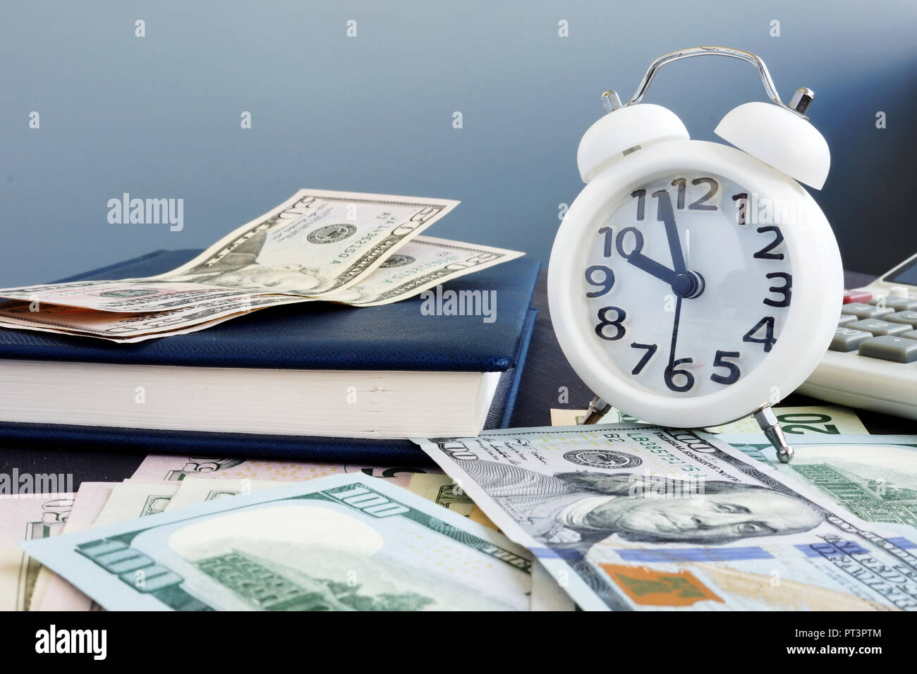 Time is money. Cash and alarm clock at the table. Stock Photo