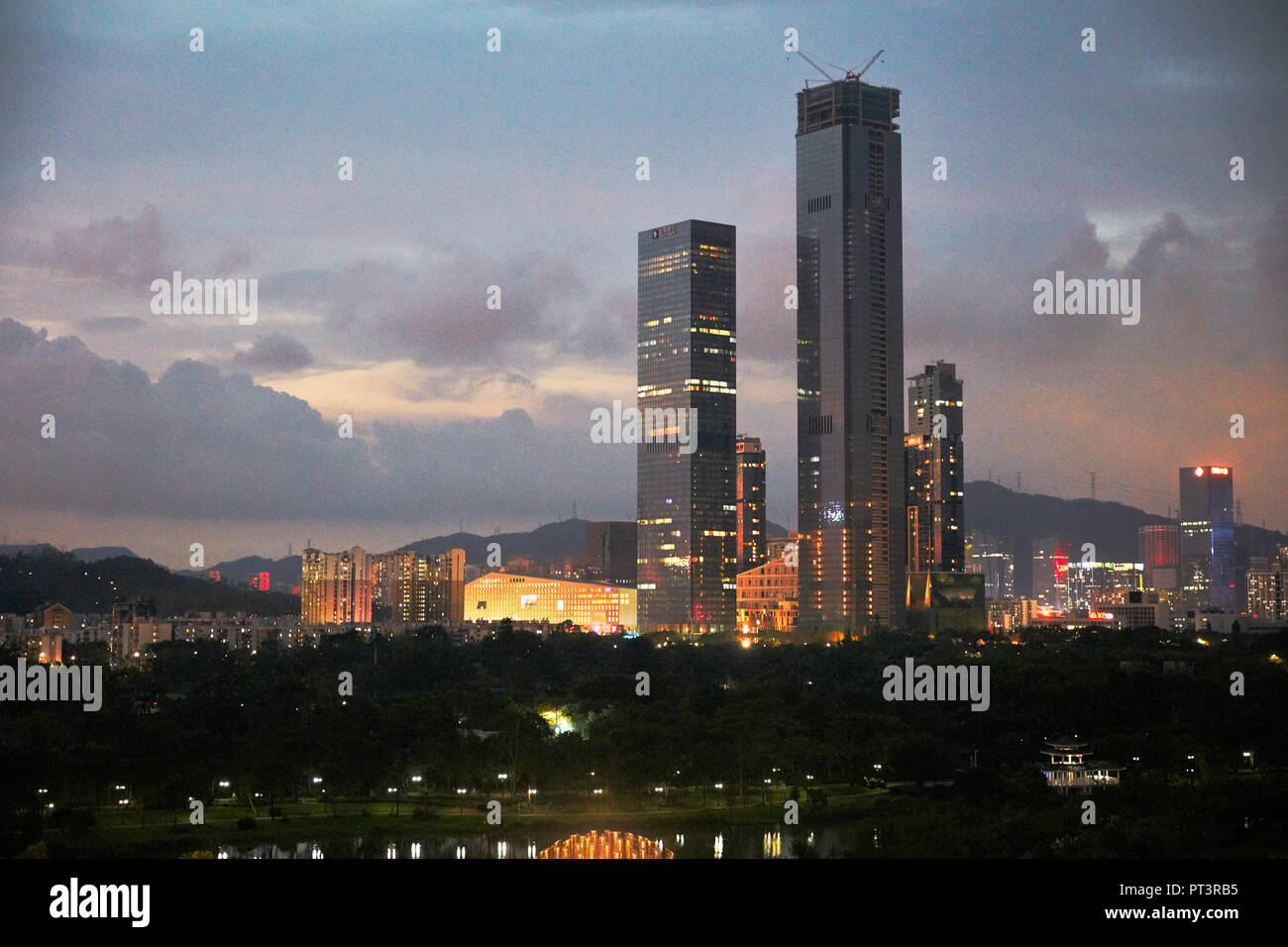 High-rise buildings in Futian District illuminated at dusk. Shenzhen, Guangdong Province, China. Stock Photo