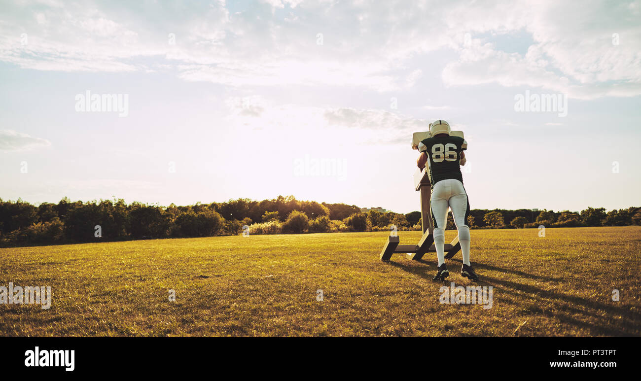 Young American football player practicing tackles and defensive drills outside on a sports field in the late afternoon Stock Photo
