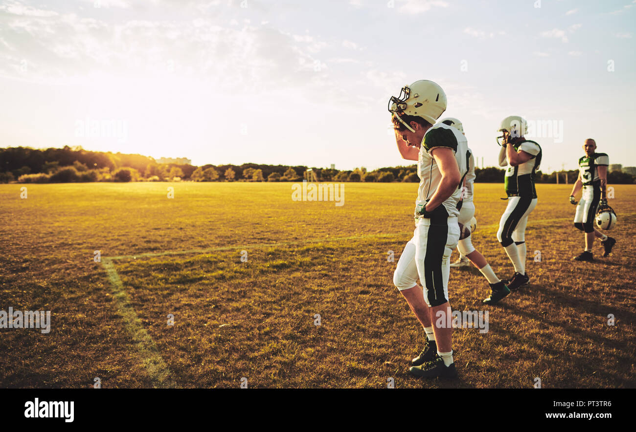 Group of young American football players taking off their helmets and