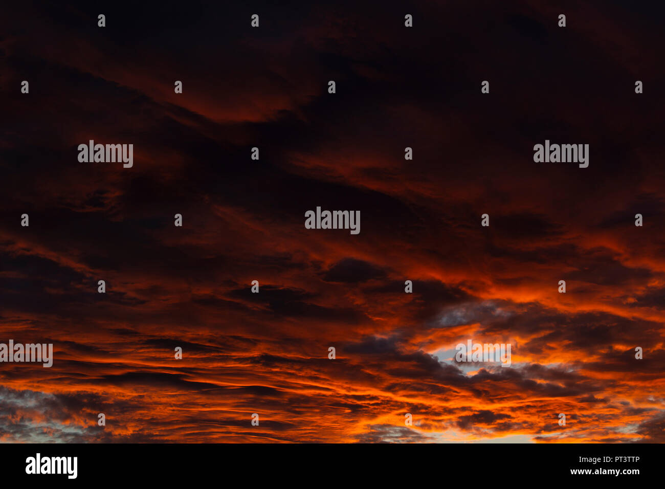 Clouds lit orange by sunset. Gradient from darker to brighter. Stock Photo