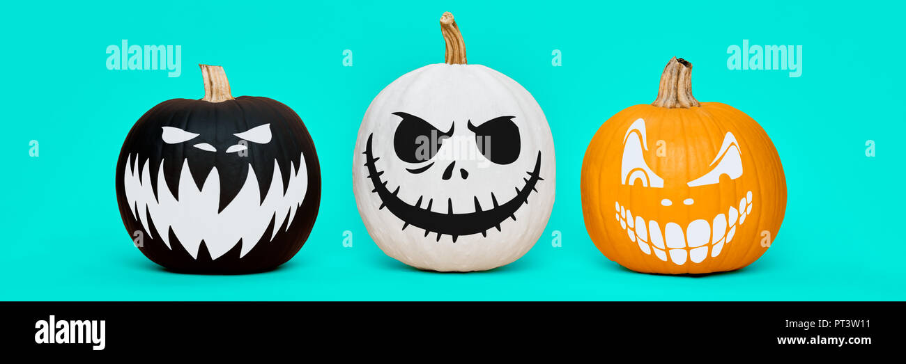 Three Spooky Halloween pumpkins with scary face expressions over pastel ...