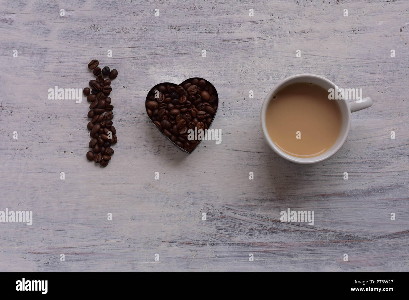 Cup op coffee and Heart shape roasted coffee beans on white rustic wooden table/ Romantic still life food design/ I love coffee Stock Photo