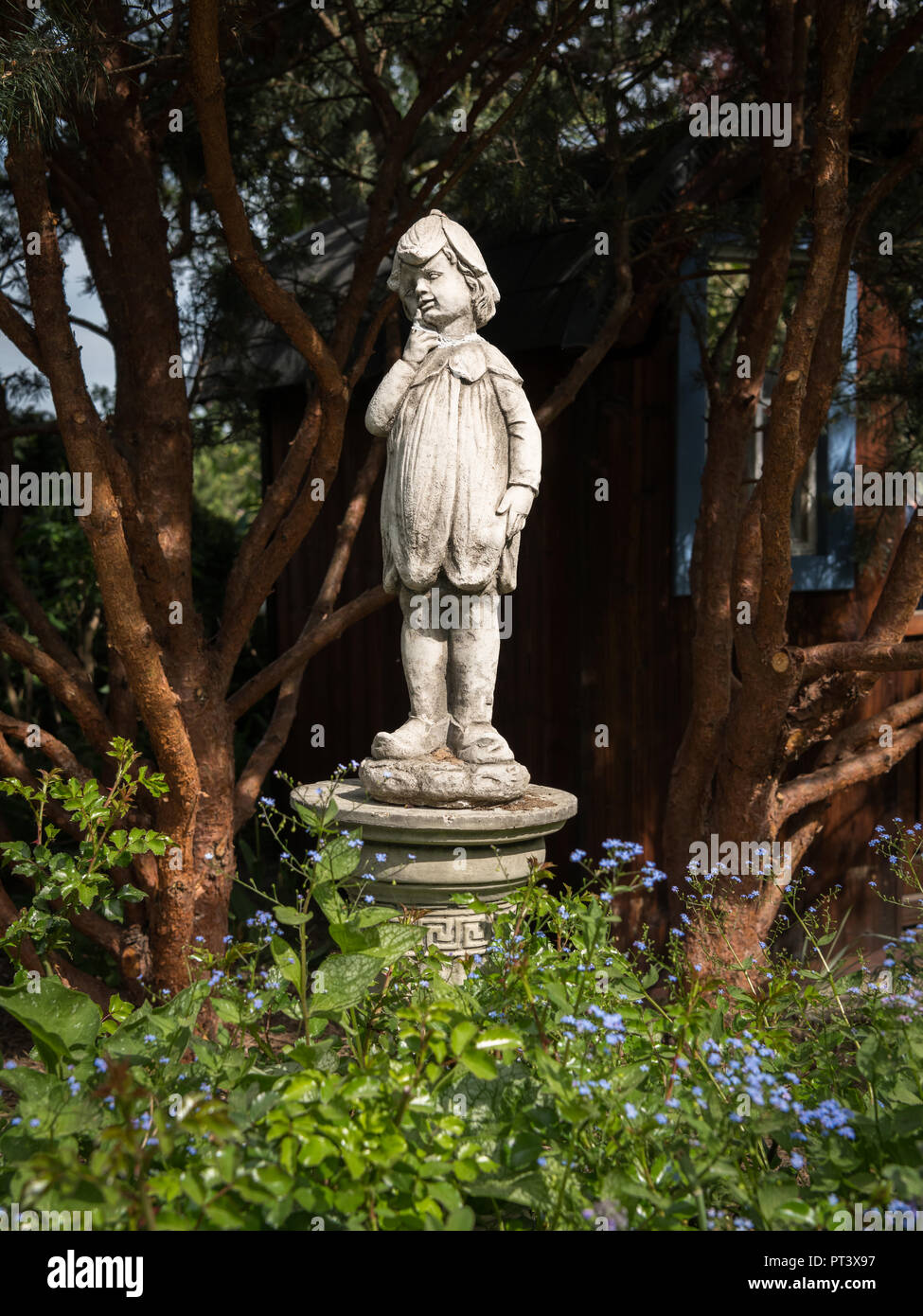 Statue of a boy made of stone standing in a garden on a sunny day in ...
