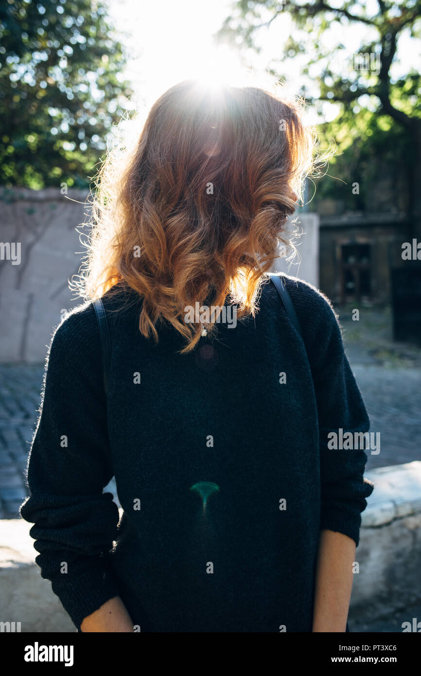 Young woman with curly light brown hair standing next to paving road in ...