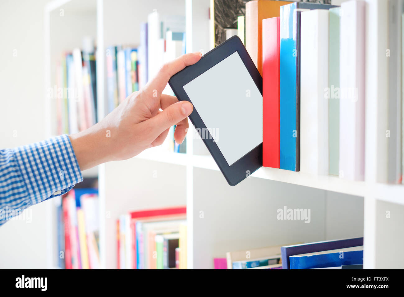 Hands holding ebook on bookshelf background.Copy space on digital tablet display Stock Photo