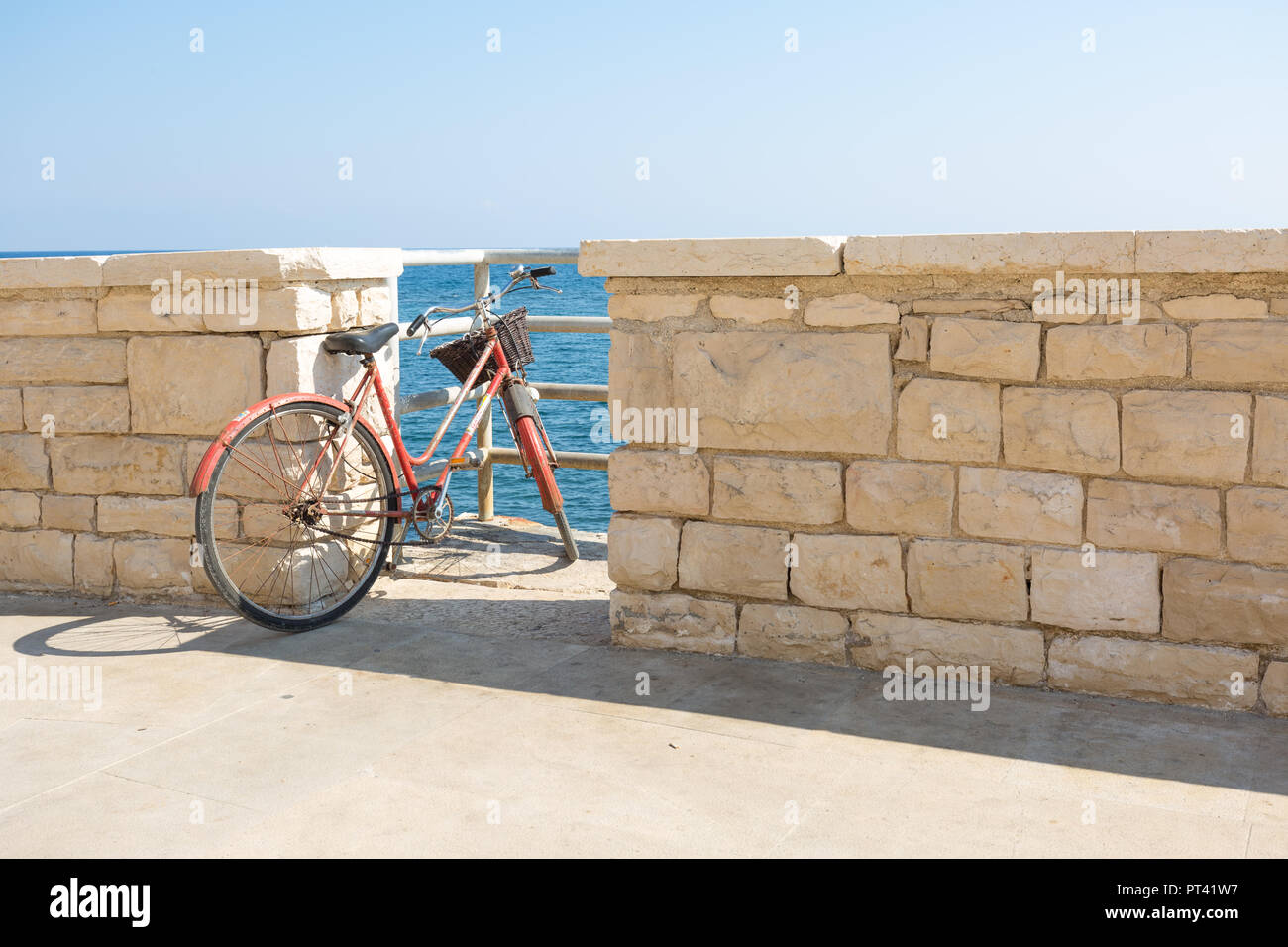 An old bike parked at access to the sea, in Giovinazzo, Puglia, Italy, Europe Stock Photo