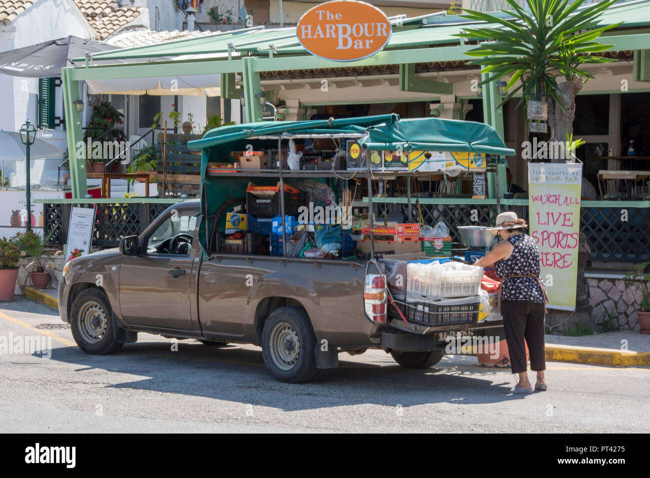 greek local lady buying fruits and vegetables from a mobile shop on a truck or pickup. Stock Photo
