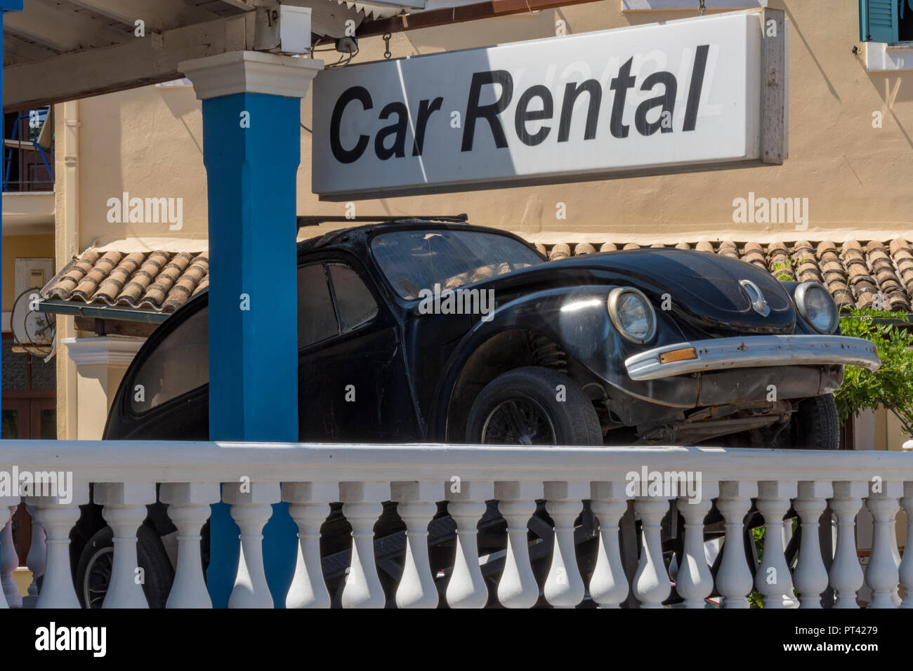 a greek care hire office with an original black Volkswagen beetle car on a ramp for advertising in Greece. Stock Photo