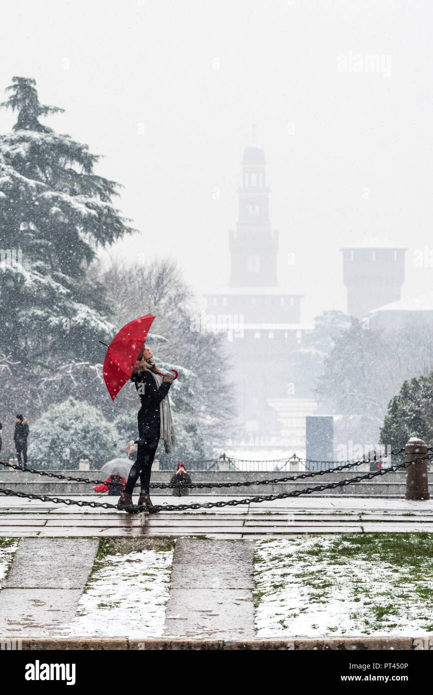 A woman with red umbrella enjoys the snowfall, Milan, Lombardy, Italy, Europe, Stock Photo