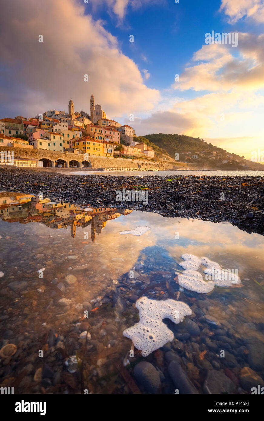 The village is reflected in a puddle on the beach during the sunrise ...