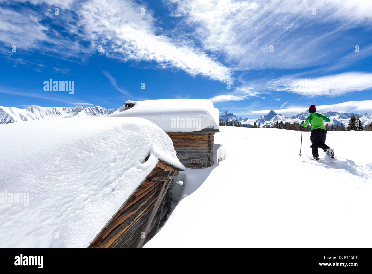 A trekker walks in the fresh snow with snowshoes near typical alpine huts, Wiesner Alp, Davos Wiesen, Landwasser Valley, Albula Valley, District of Prattigau / Davos, Canton of Graubünden, Switzerland, Europe, Stock Photo