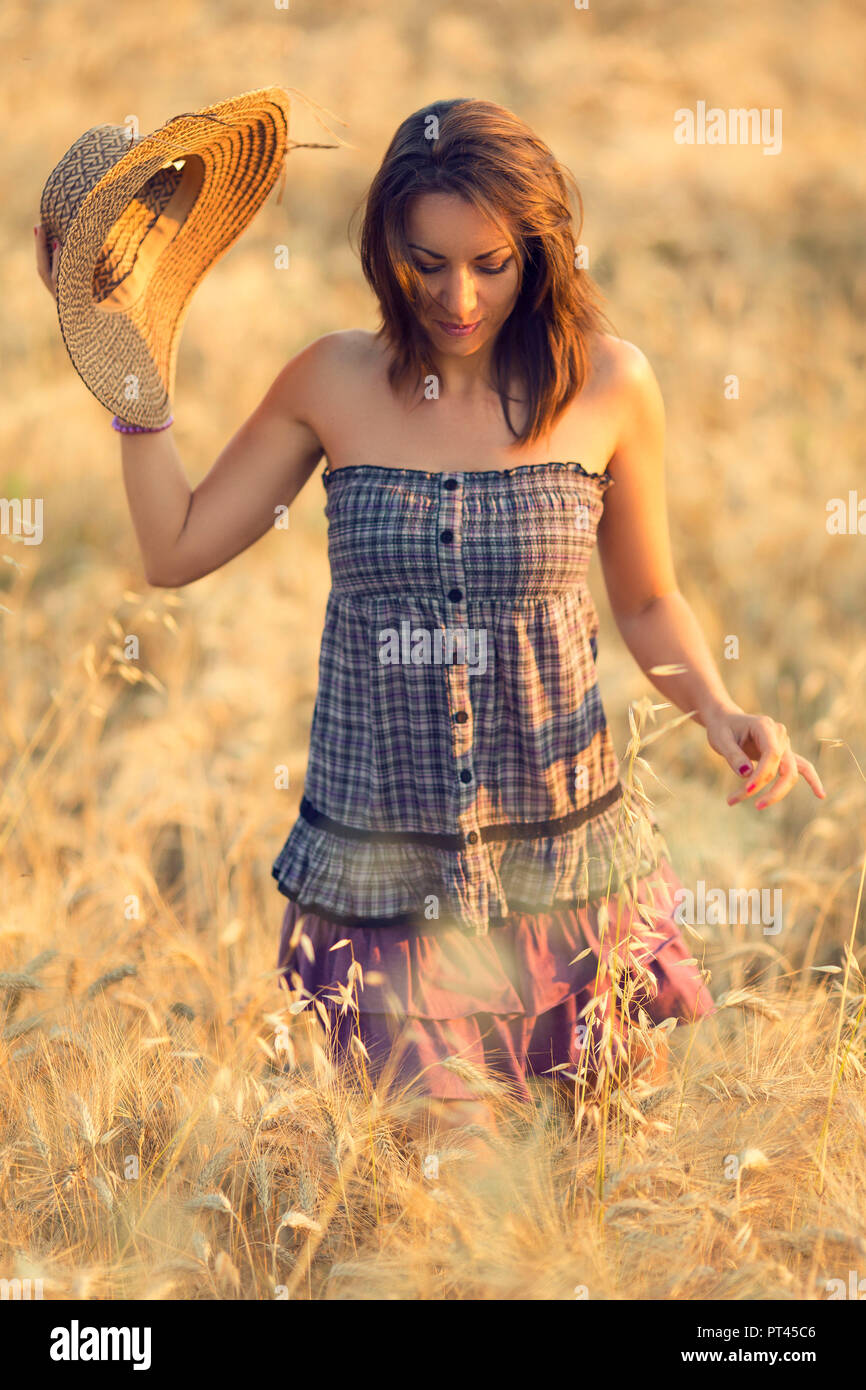 Brunette woman in purple dress in a wheat field at sunset, marche, Italy Stock Photo