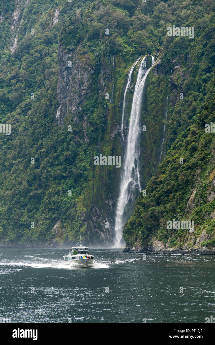 Touristic boat and Stirling Falls in Milford Sound, Fiordland NP, Southland district, Southland region, South Island, New Zealand, Stock Photo