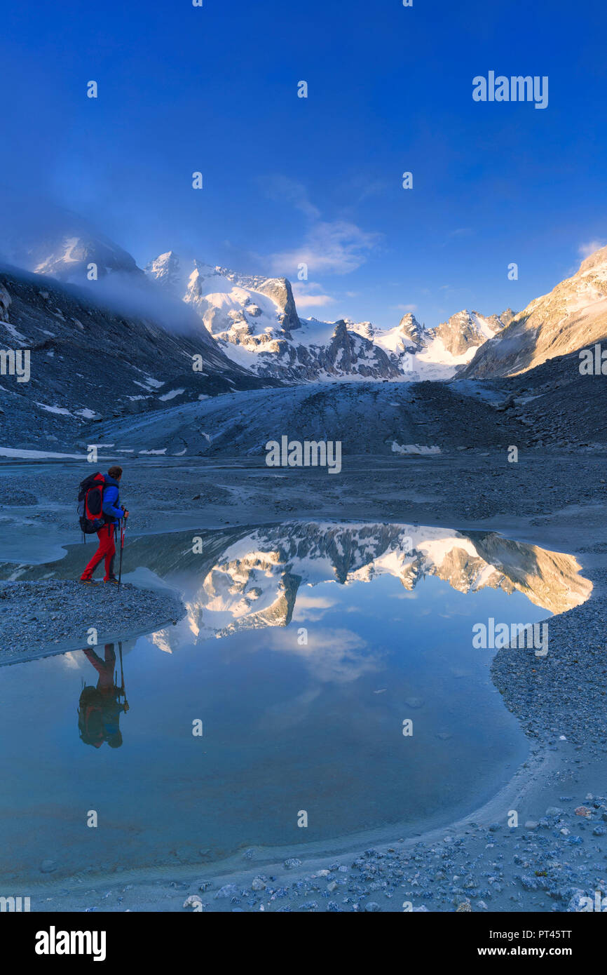 Hikers looks sunrise from a pond at Forno Glacier, Forno Valley, Maloja Pass, Engadin, Graubünden, Switzerland, Europe, Stock Photo