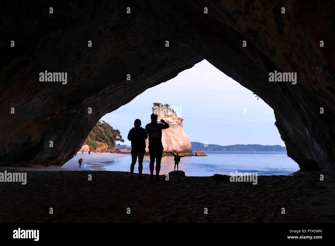 Three people's silhouette taking photographs at Cathedral Cove, Hahei, Waikato region, North Island, New Zealand, Stock Photo