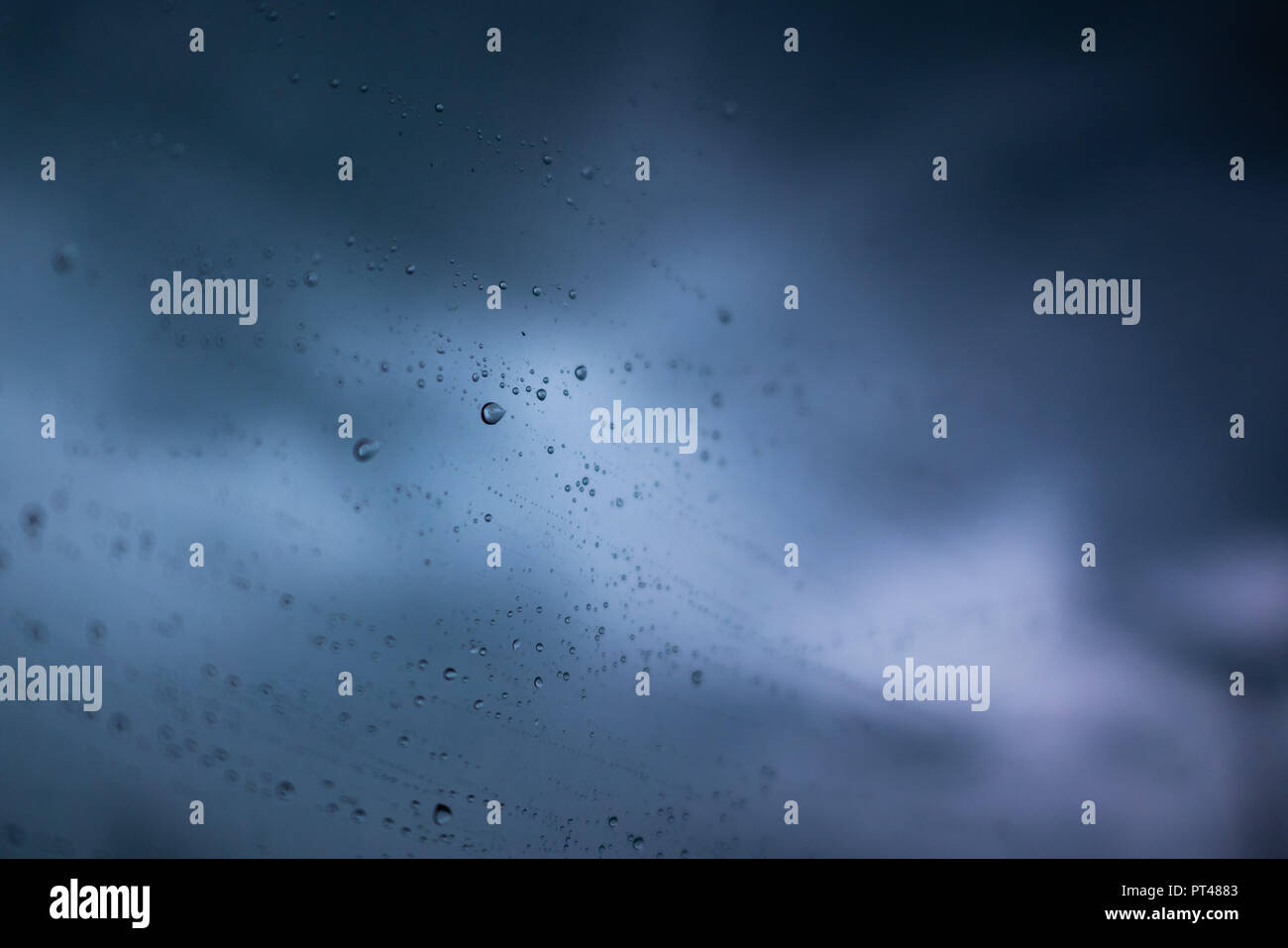 Rain drops on window with dark blue sky Stock Photo